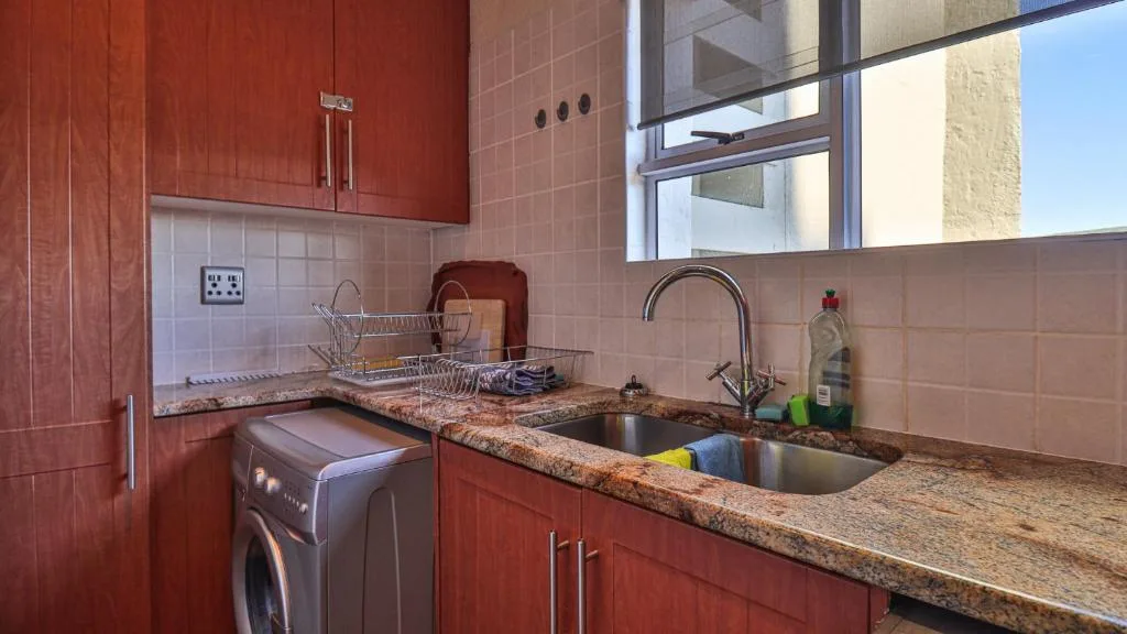 Modern kitchen with red cabinets, granite countertops, and stainless steel sink