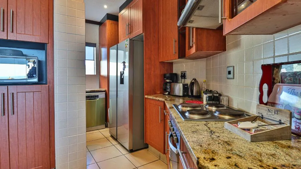 Modern kitchen with wooden cabinets, granite countertops, stainless steel appliances