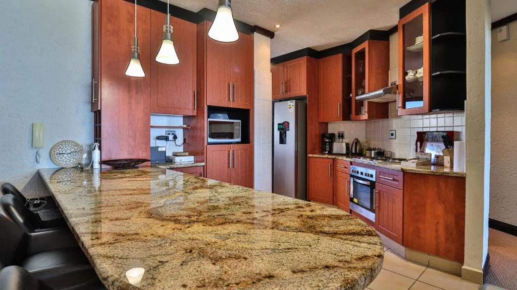 Modern kitchen with granite countertop, red wood cabinetry, stainless steel appliances
