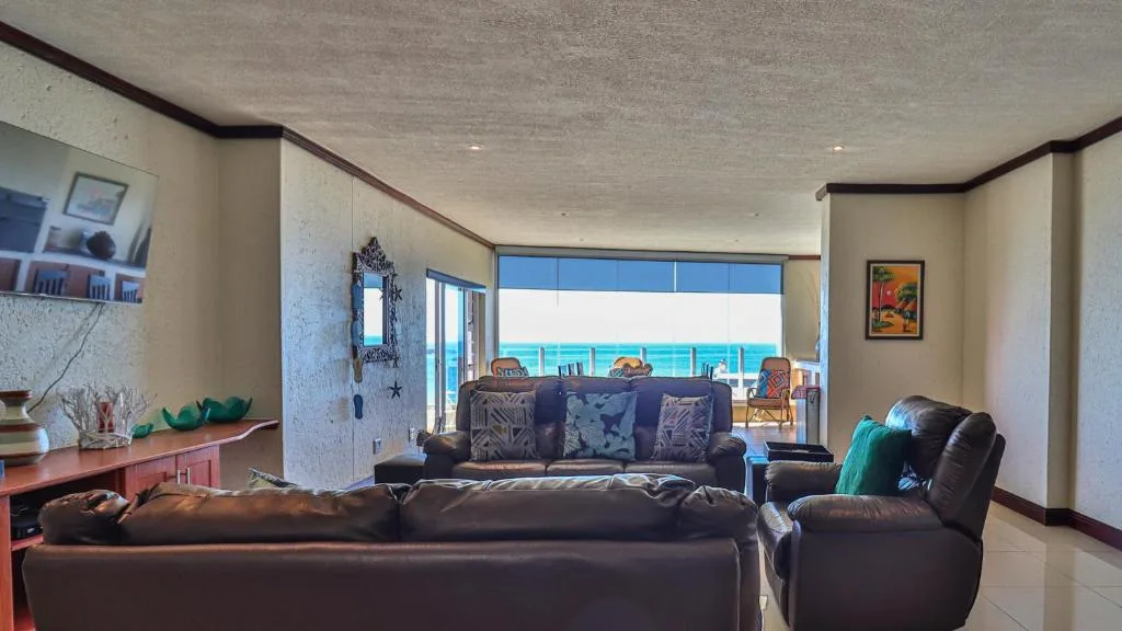 Spacious lounge with dark leather seating and ocean views through large windows