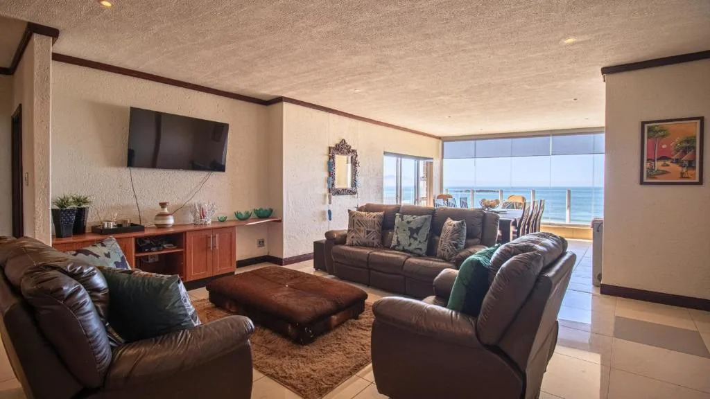 Spacious lounge with leather seating, ocean views through glass doors