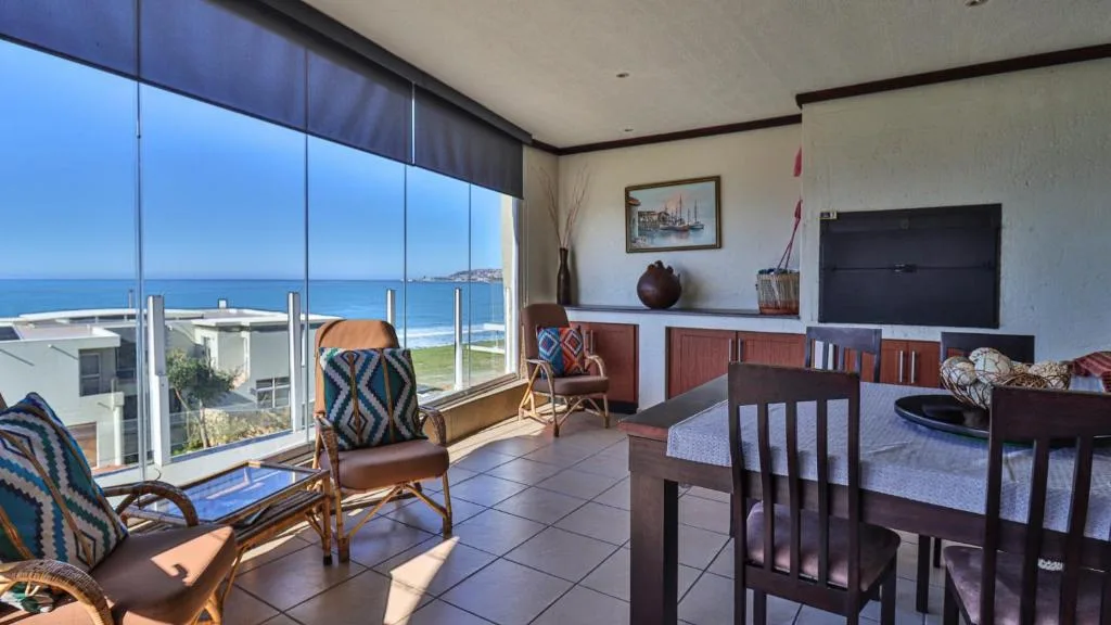 Spacious lounge with sea views through floor-to-ceiling windows overlooking beach