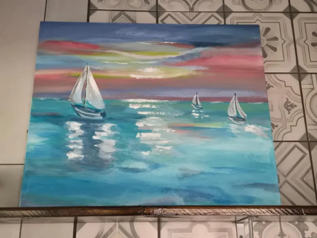 Colorful seascape painting with sailboats at sunset displayed indoors