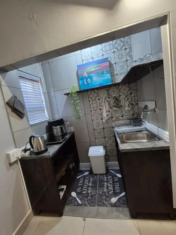 Compact kitchenette with black cabinetry, sink, coffee maker, kettle