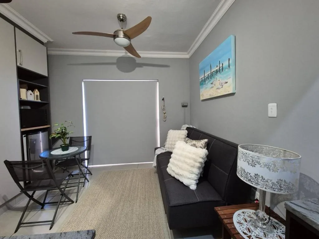 Modern lounge with black sofa, ceiling fan, work desk, and beach artwork