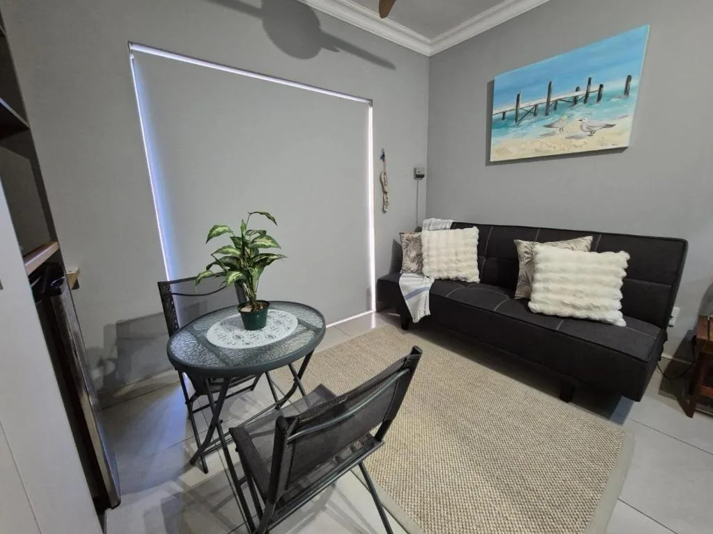 Modern lounge with black sofa, decorative cushions, and coastal artwork
