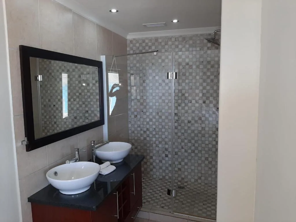 Modern bathroom with dual vessel sinks, framed mirror, and walk-in shower
