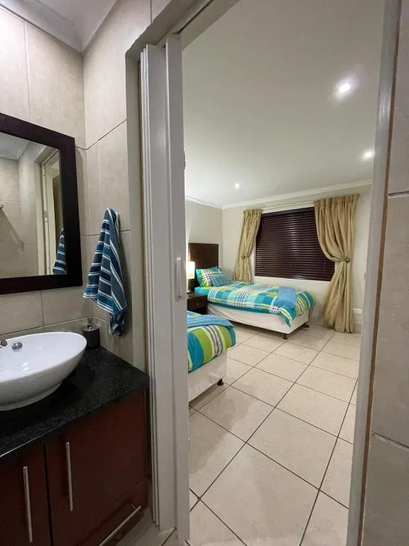 Modern bathroom with round sink, dark vanity, and view into adjacent bedroom