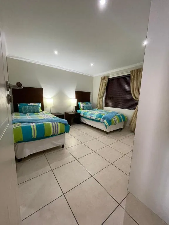 Twin bedroom with striped bedding, dark headboards, and recessed ceiling lights