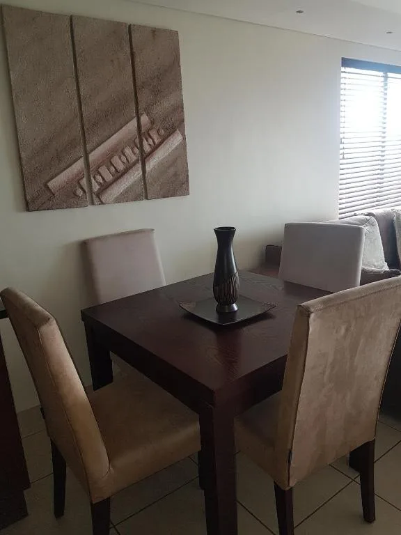 Dark wooden dining table with upholstered chairs and black vase centerpiece