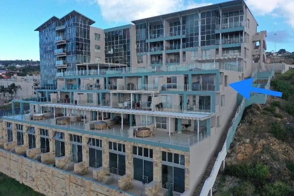 Modern multi-story beachfront apartment building with turquoise balconies and glass features