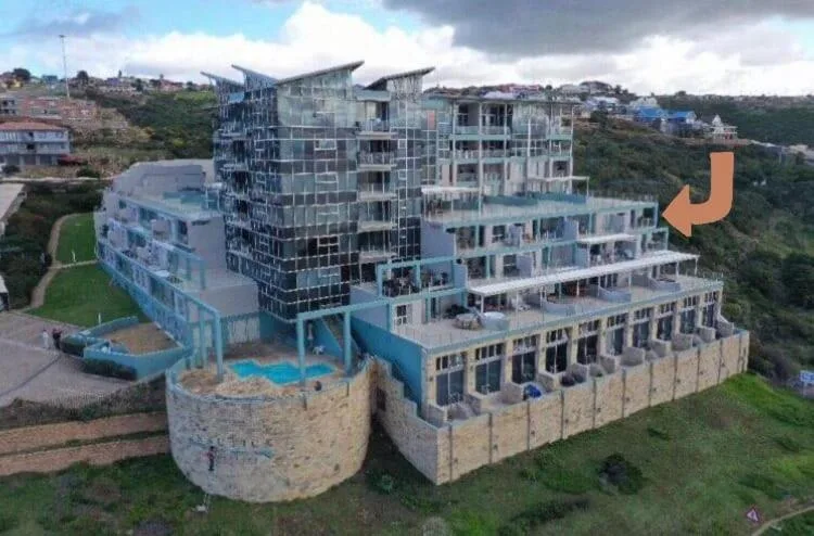 Modern multi-story apartment building with curved facade overlooking Mossel Bay coastline