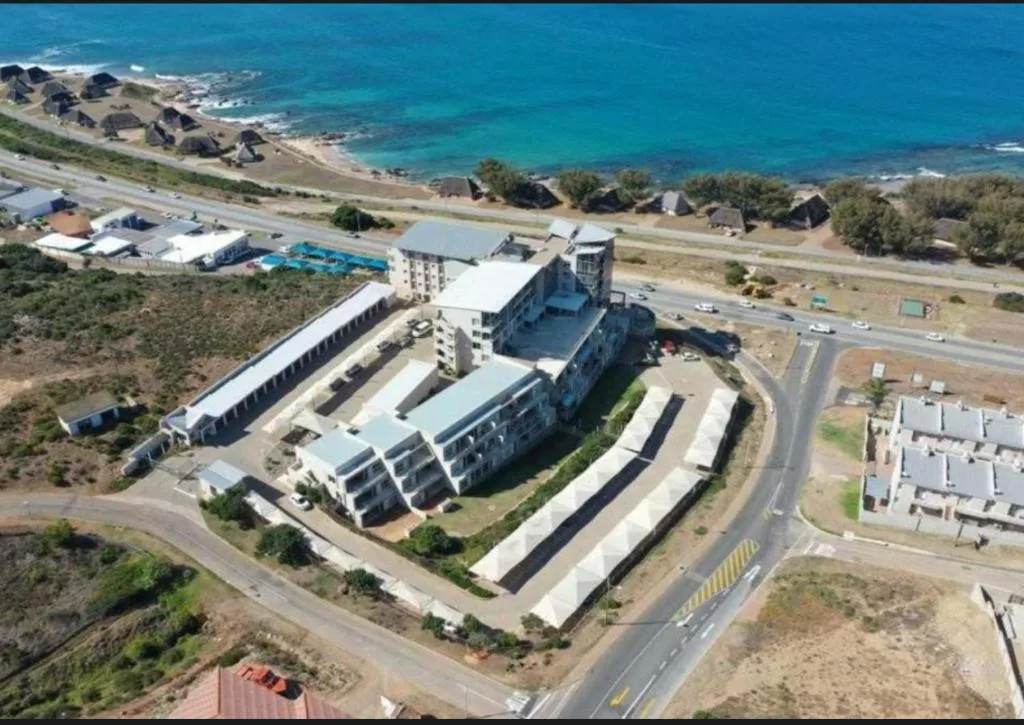 Aerial view of beachfront apartment complex with ocean and coastal buildings visible