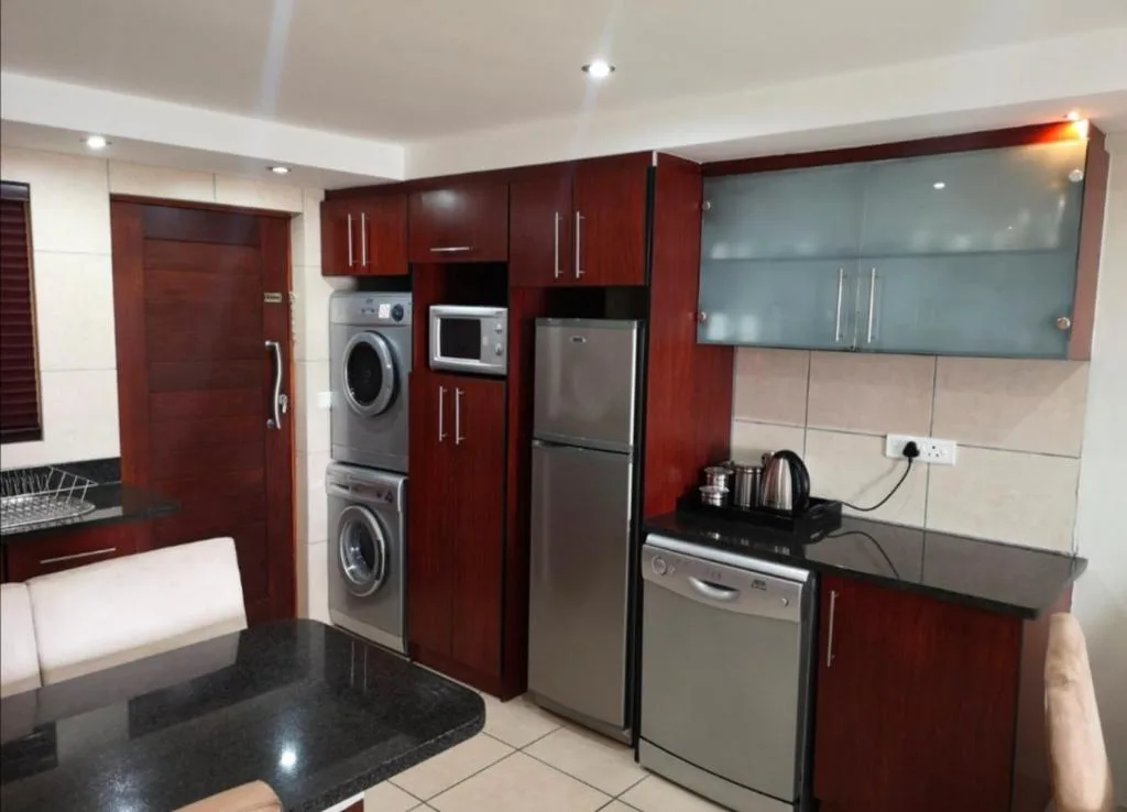 Modern kitchen with dark red cabinetry, stainless steel appliances, and black countertop