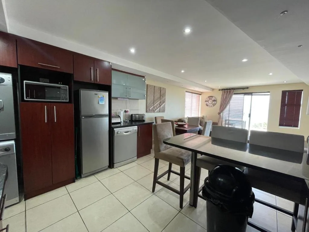 Modern kitchen with red cabinetry, stainless steel appliances, and dining area