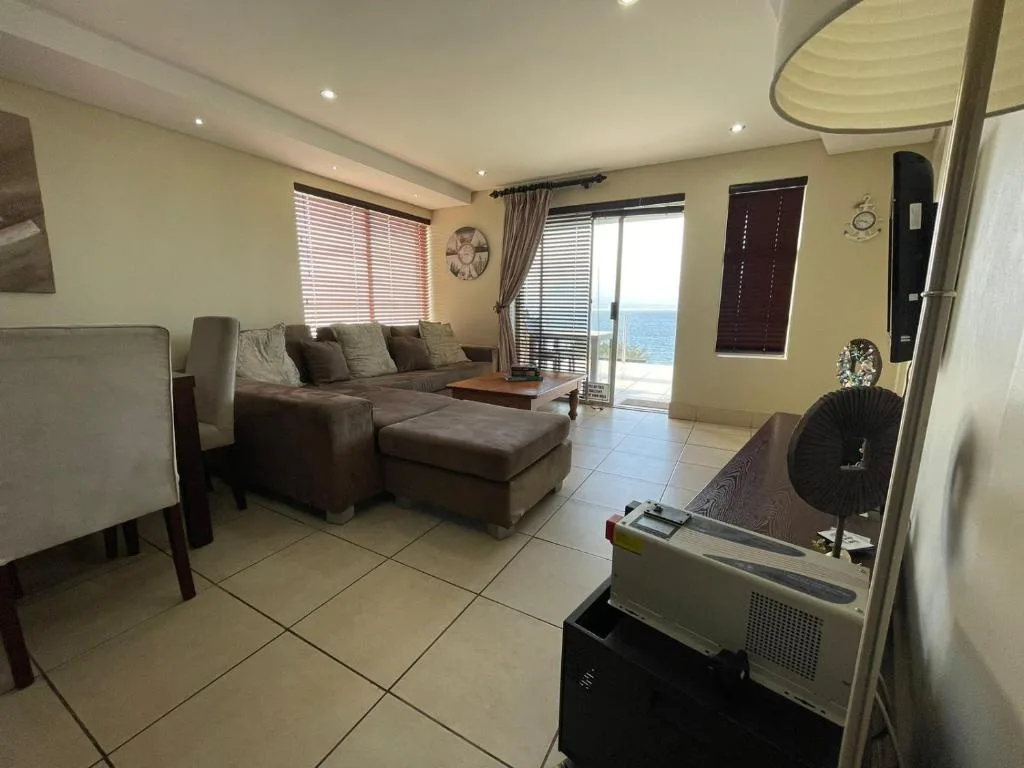 Spacious lounge with brown sectional sofa and ocean view through glass doors