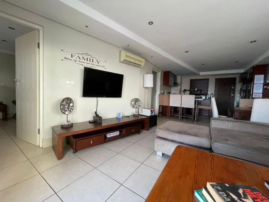Open-plan living room with TV, comfortable seating, and kitchen area visible