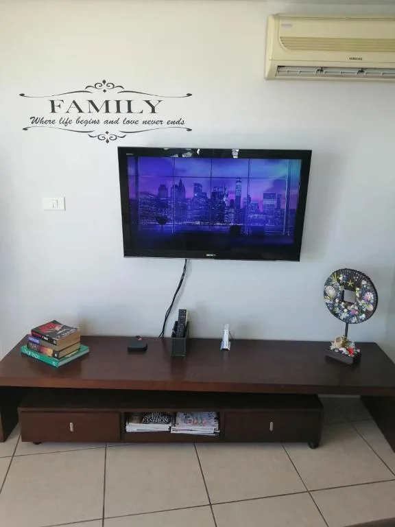 Living room with wall-mounted TV, wooden entertainment unit, and family wall decor
