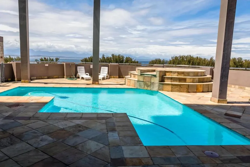 Turquoise swimming pool on expansive deck with mountain ocean views