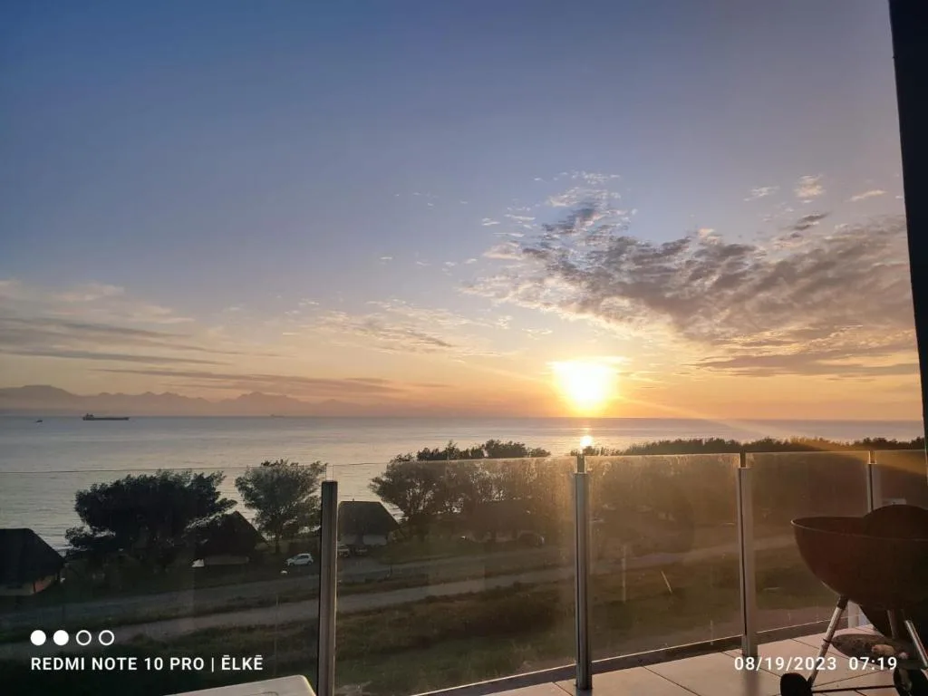 Stunning ocean sunset view from coastal deck with mountains in distance