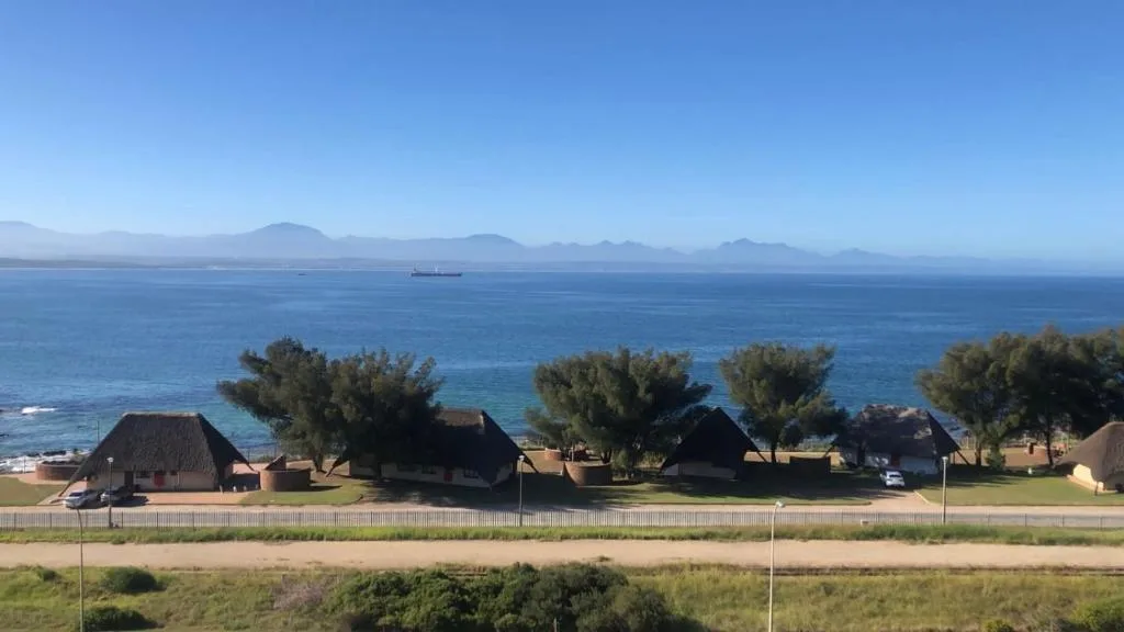 Ocean view with mountains and thatched-roof cottages along the coastline