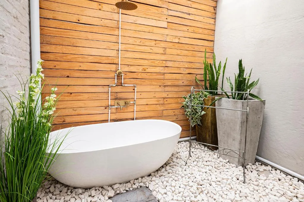 Modern freestanding bathtub with wooden feature wall and potted plants