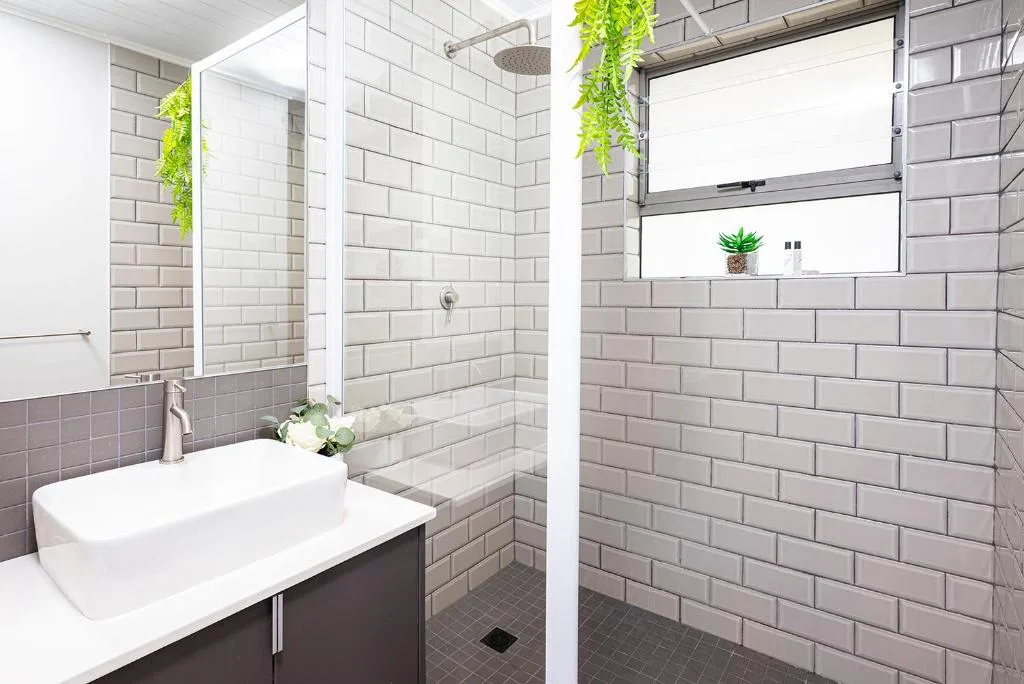 Modern bathroom with white vanity sink, mirrored cabinet, and tiled shower area