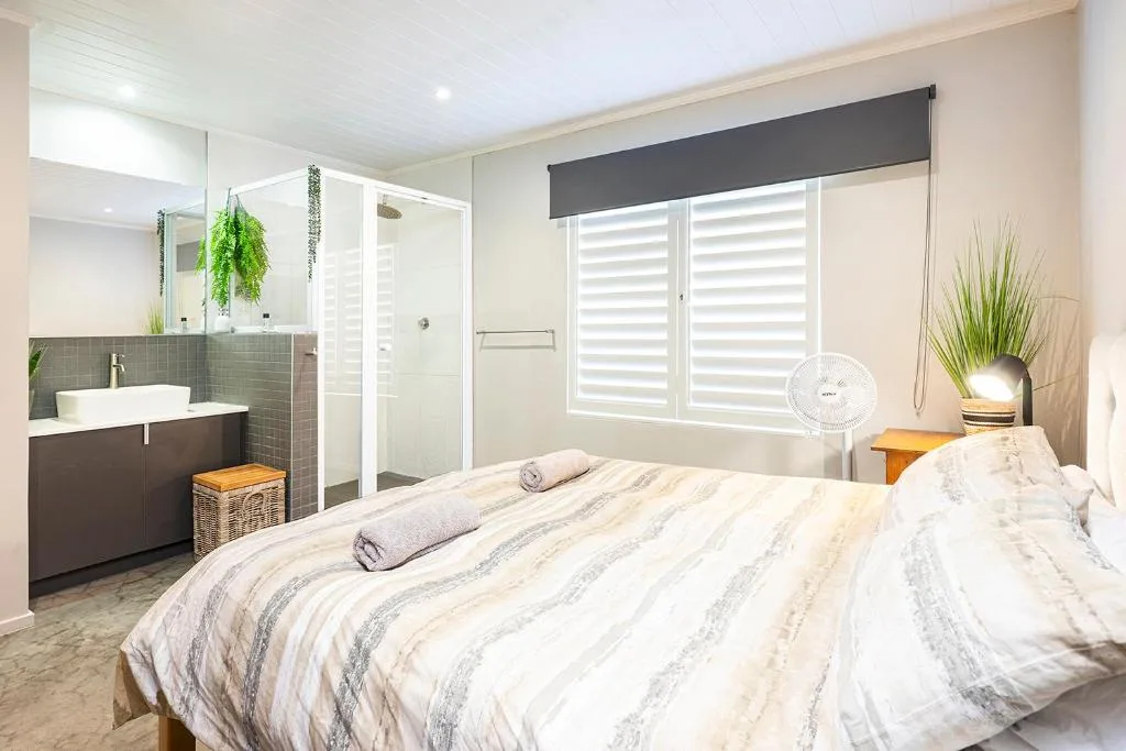 Bright bedroom with en-suite bathroom, modern shutters, and potted plants