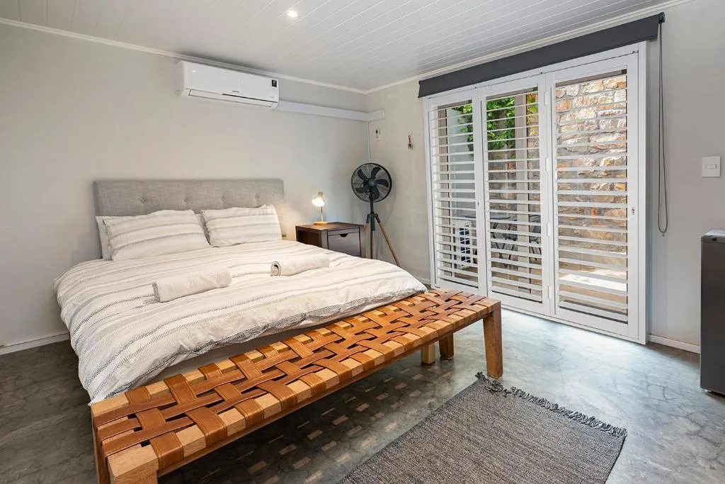 Modern bedroom with queen bed, shuttered glass doors, air conditioning unit