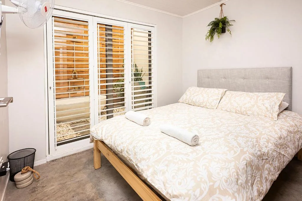 Bright bedroom with queen bed, patterned bedding, and glass doors opening to patio