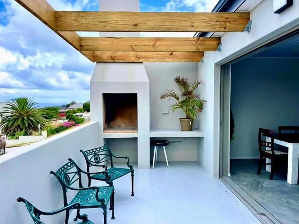 Covered deck with wooden pergola, seating, fireplace, and ocean views