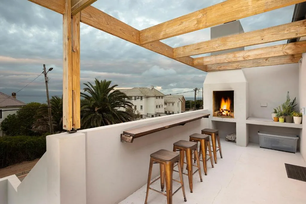 Outdoor rooftop deck with wooden pergola, bar seating, and ocean views