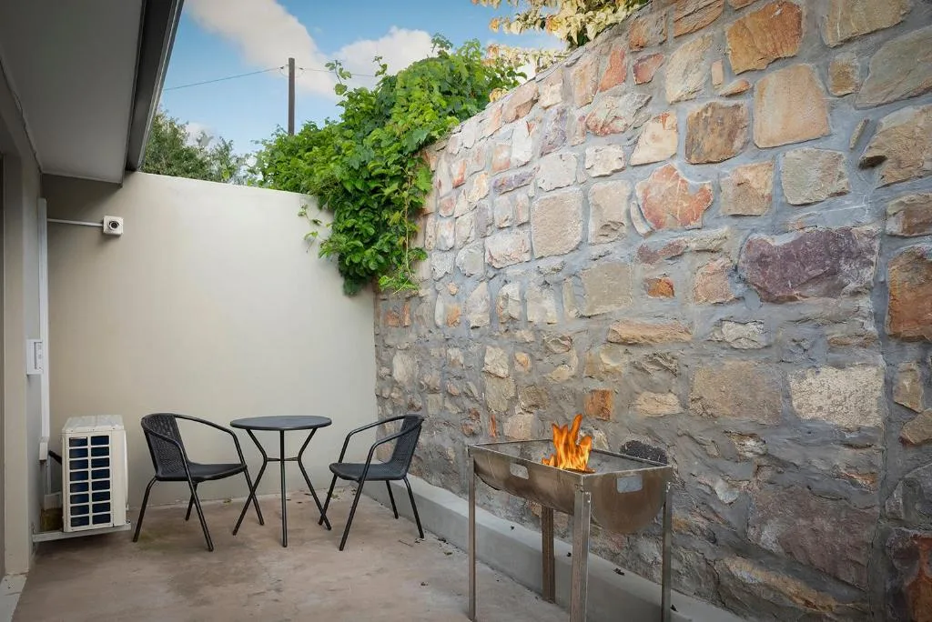 Outdoor patio with seating, firepit, and rustic stone wall