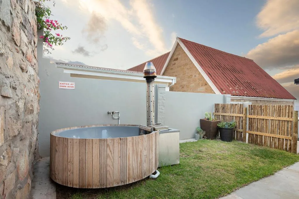 Wooden hot tub with heating system in fenced garden area