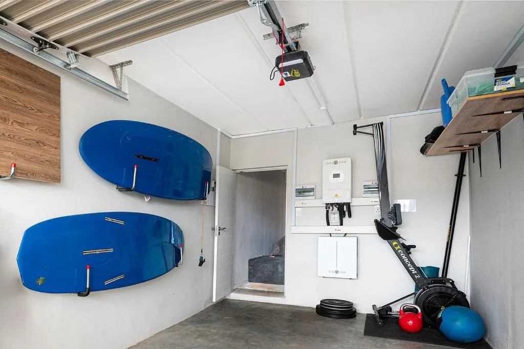 Garage interior with blue kiteboarding boards, exercise equipment, and storage