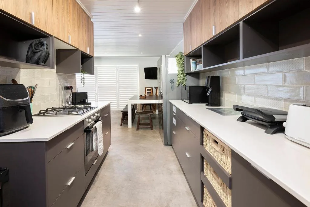 Modern kitchen with gas stove, white countertops, wooden cabinetry, and brick backsplash