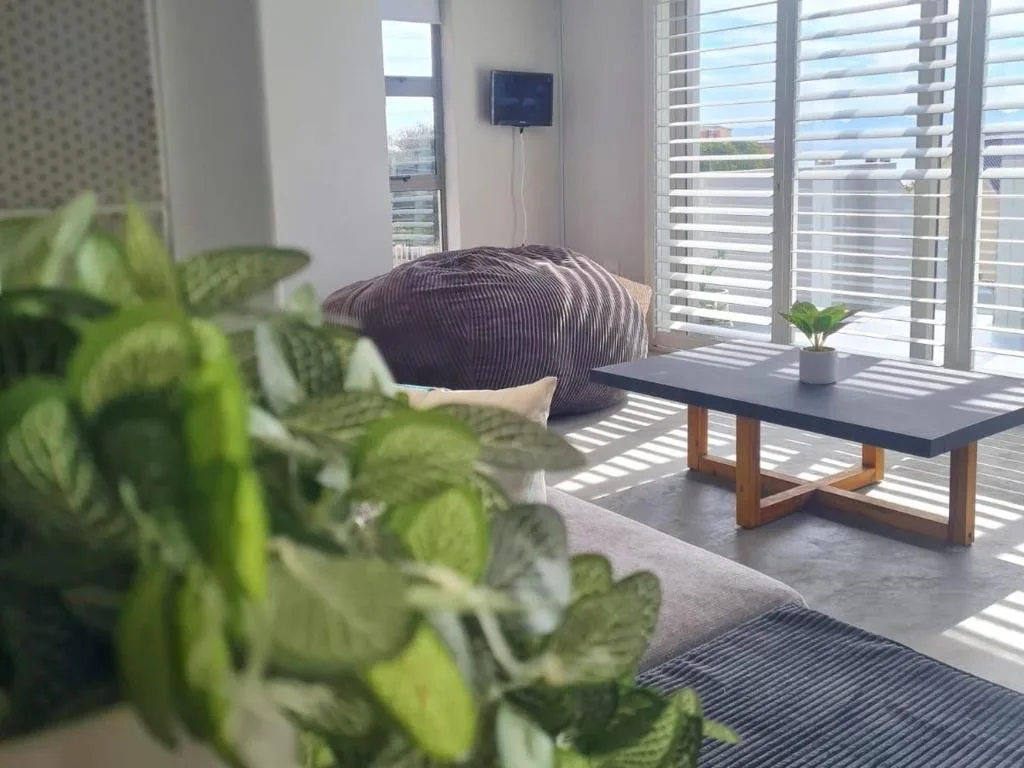 Modern lounge with bean bag chair, TV, potted plants, and ocean views