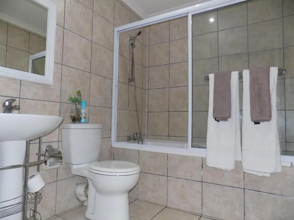 Modern bathroom with tiled walls, toilet, sink, and shower cubicle