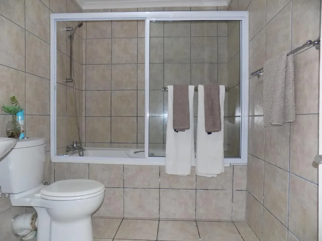 Modern bathroom with enclosed shower, toilet, and towel rails