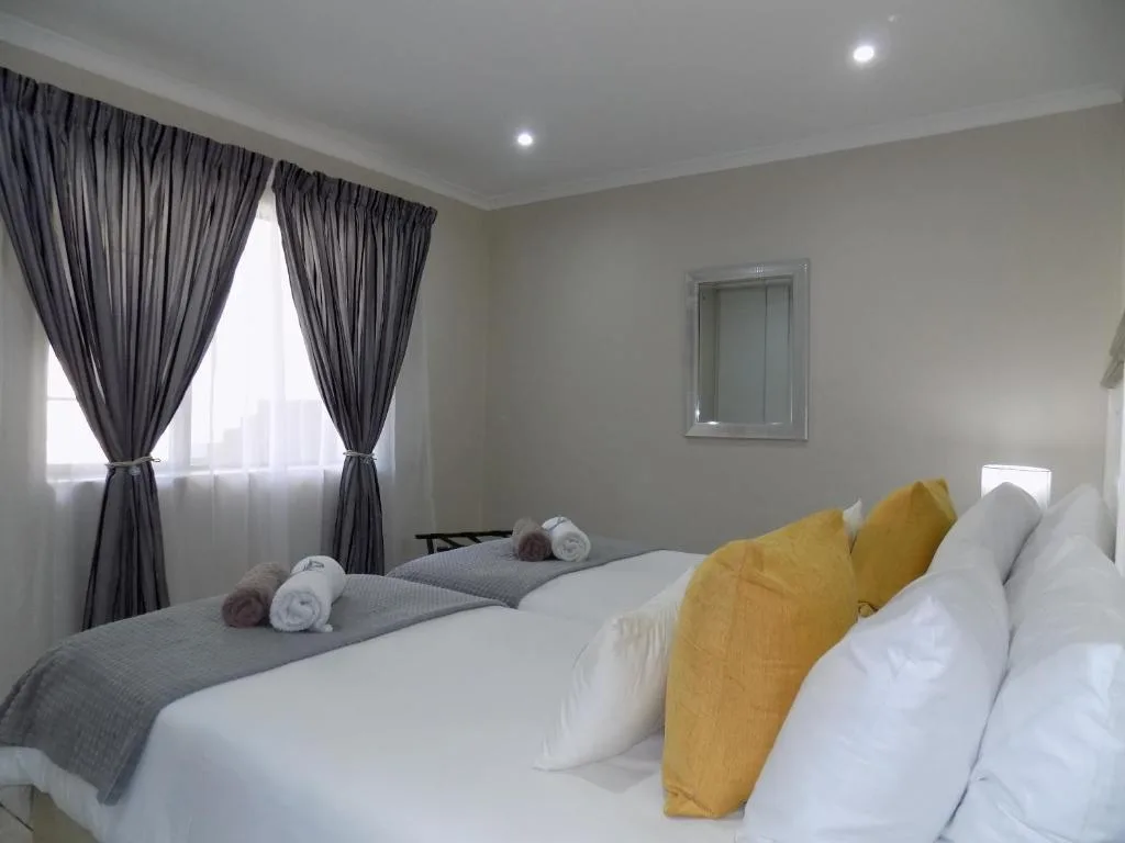 Bright bedroom with twin beds, yellow pillows, and dark curtains