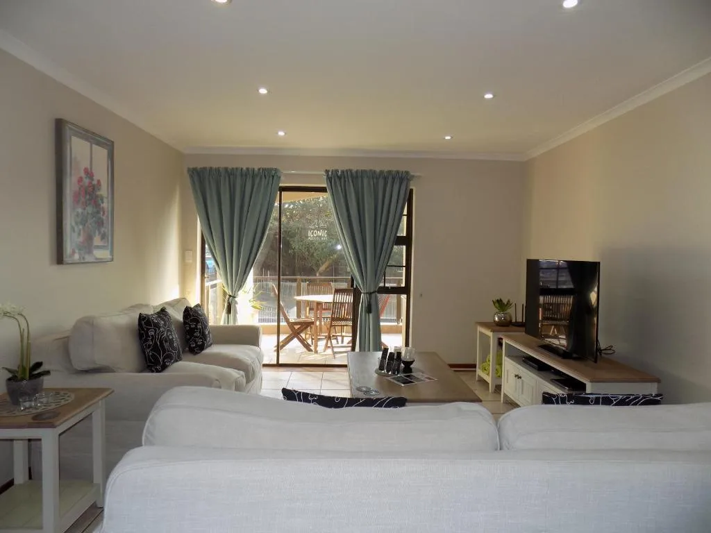 Modern bedroom with twin beds, lounge area, and doors opening to deck