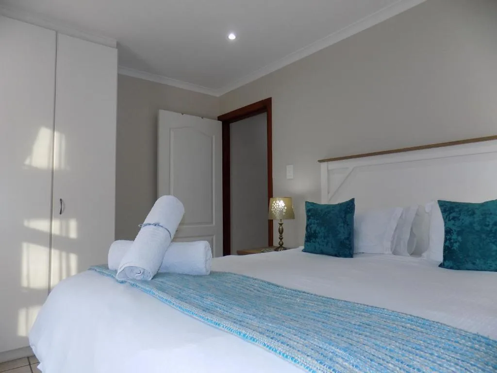 Bright bedroom with double bed, teal pillows, and white linens