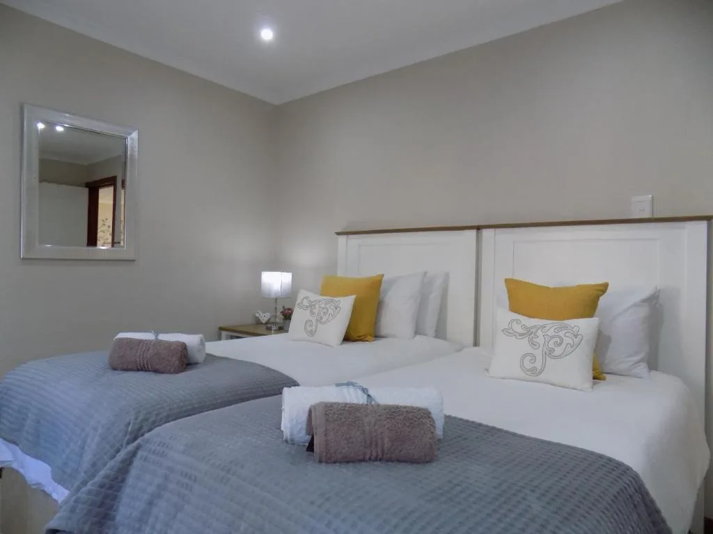 Twin beds with white headboards and yellow accent pillows in bright bedroom
