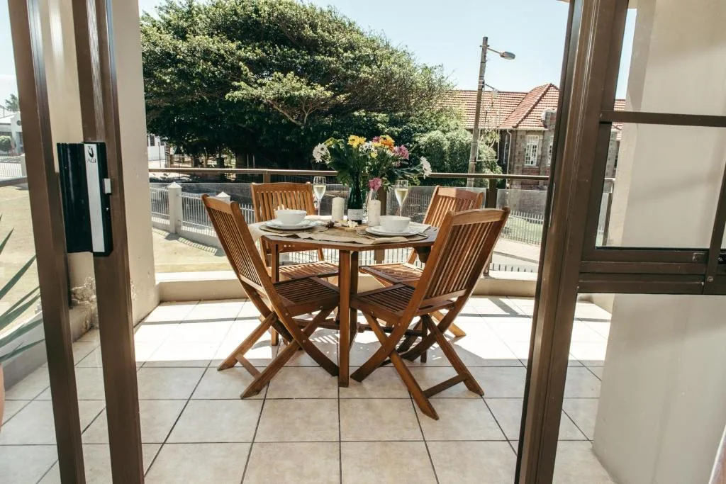 Wooden dining table and chairs on covered patio with garden views