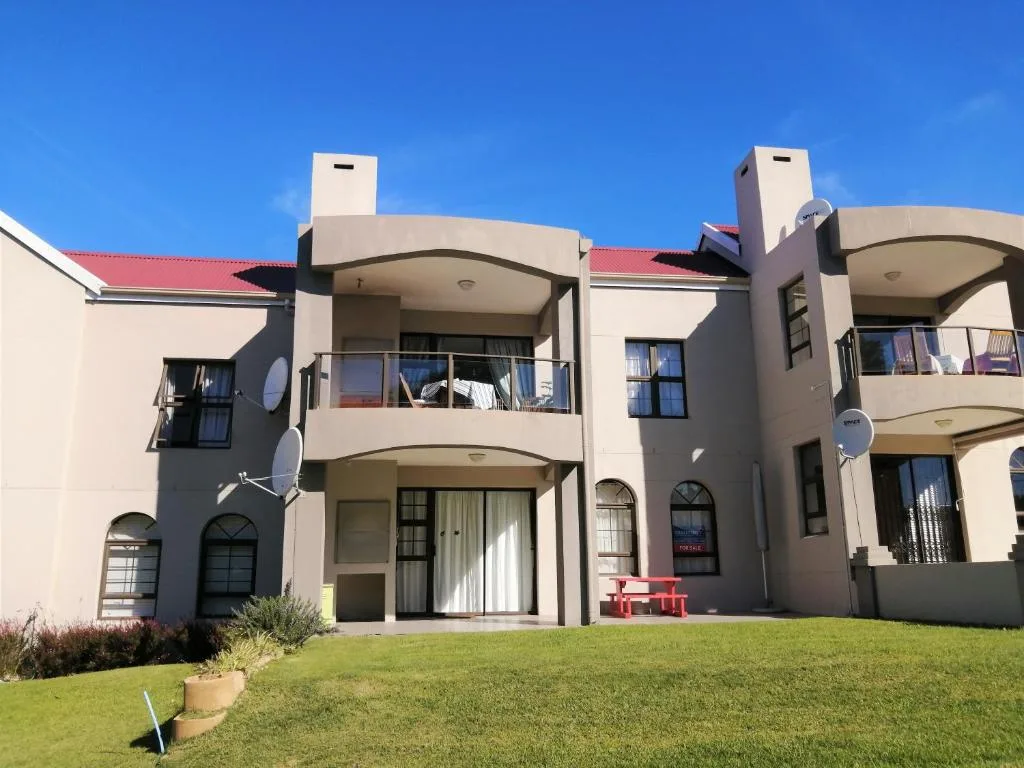 Modern cream and red residential building with curved balconies and manicured lawn