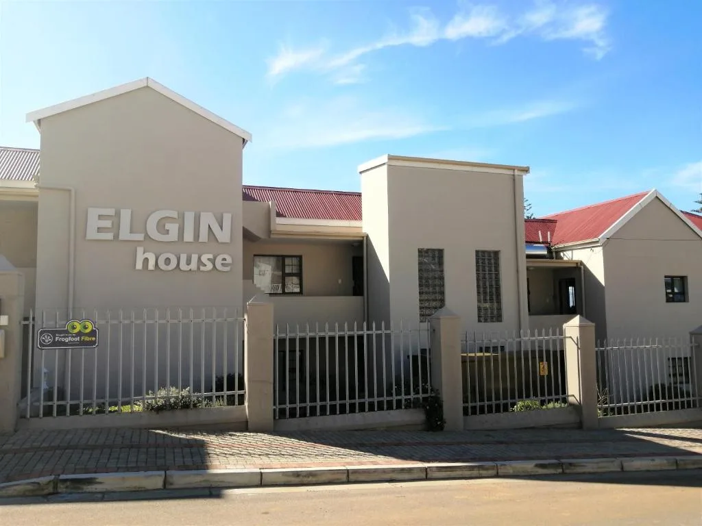 Modern beige townhouse with white gates and red roof accent
