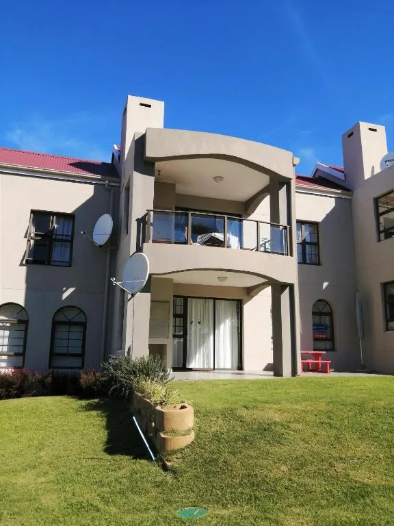 Modern white apartment building with curved balconies and manicured lawn