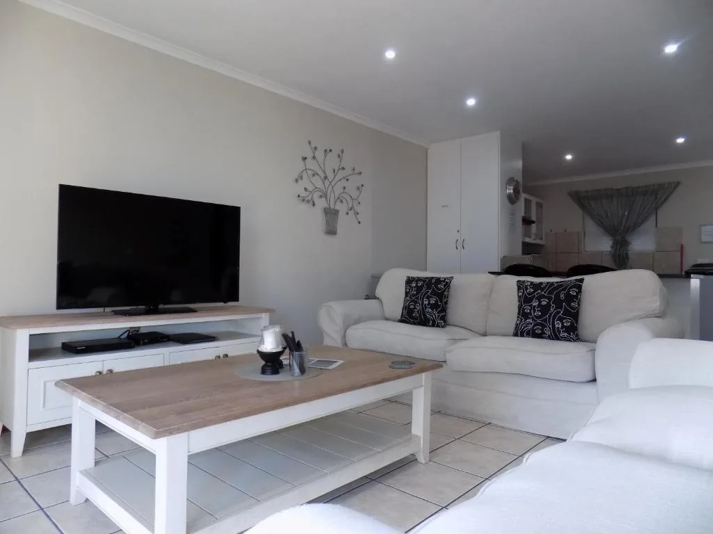 Bright lounge with cream sofa, flat-screen TV, and wooden coffee table