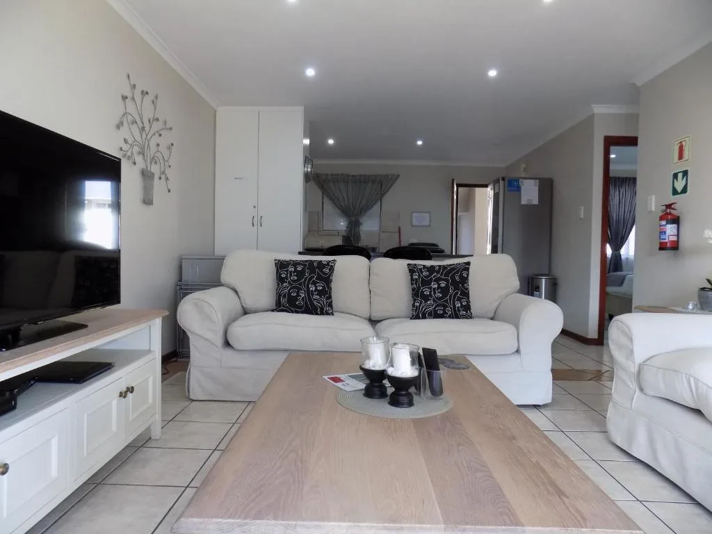 Modern lounge with cream sofa, TV, wooden coffee table and neutral decor