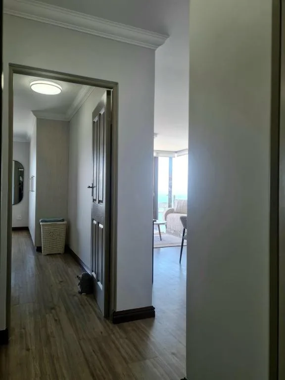 Bright hallway with wooden floors and white walls leading to rooms